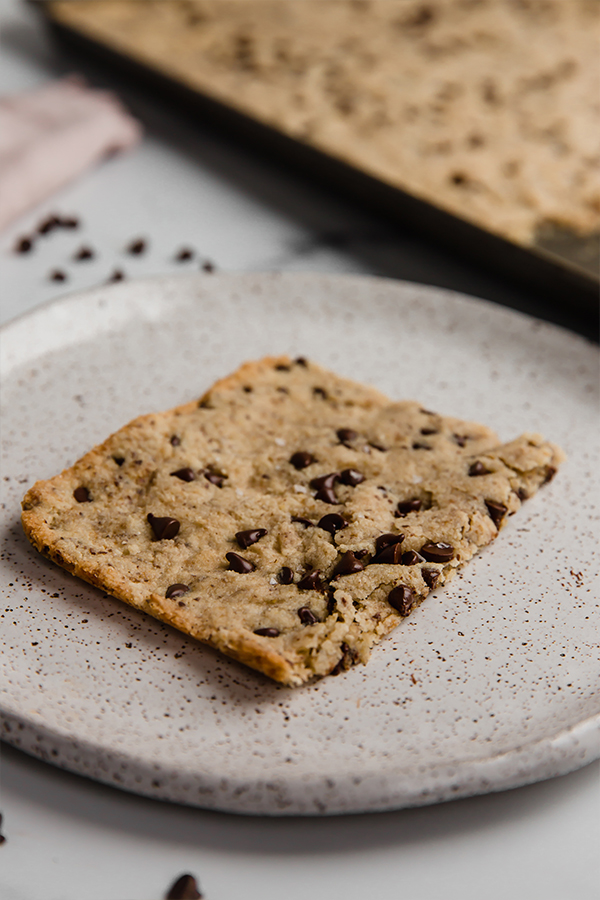 A slice of sheet pan cookie on a speckled plate.