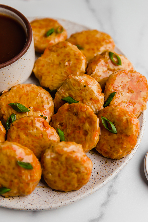Sweet and soup chicken poppers on a plate with a side of sauce.