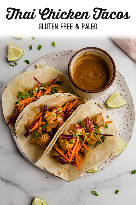 Three thai chicken tacos on a plate with sauce on the side.