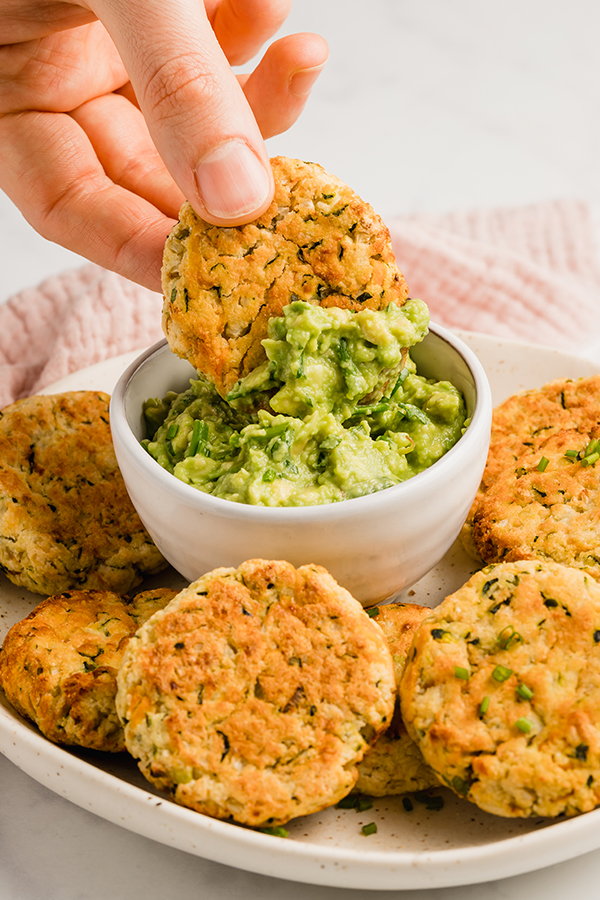 baked veggie nuggets on a plate with one being dipped into guacamole