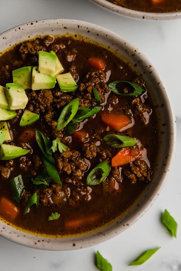 Asian chili topped with avocado in a bowl.