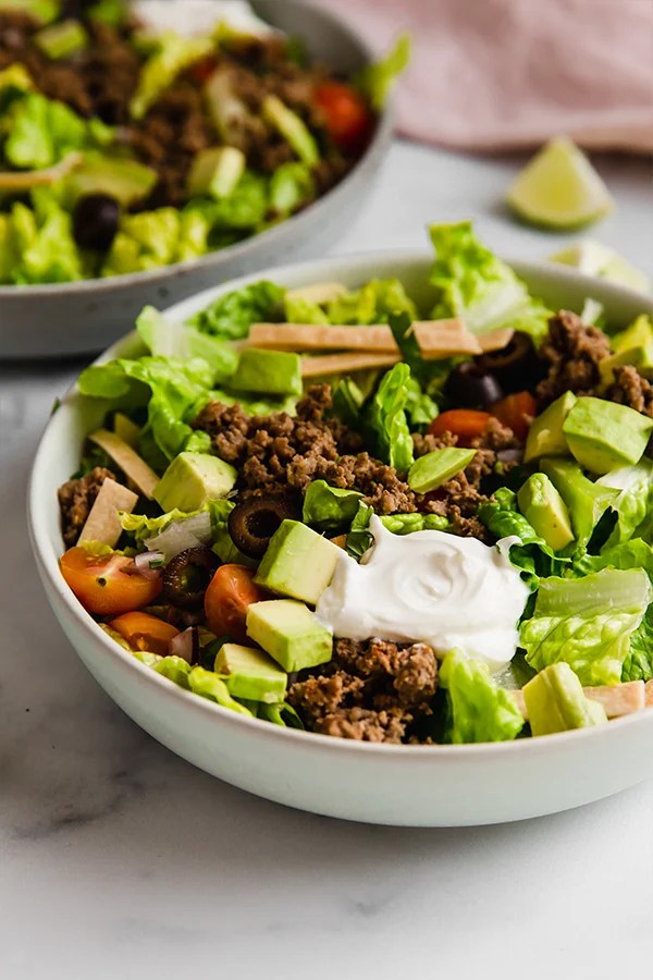 Taco salad with avocado and olives in a bowl.
