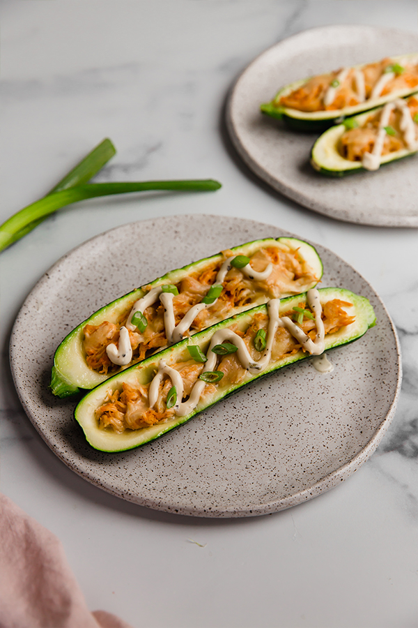 Buffalo chicken stuffed zucchini boats on a plate.