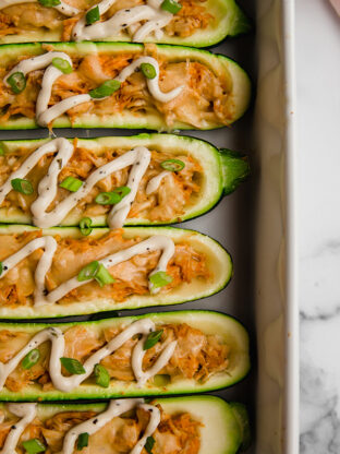 Buffalo chicken stuffed zucchini boats in a baking dish.