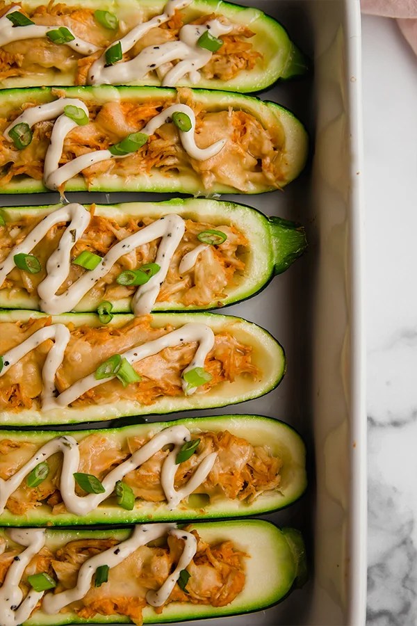 Buffalo chicken stuffed zucchini boats in a baking dish.