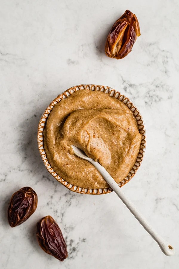Spoon in a bowl of date and coconut milk caramel.