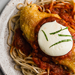 Chicken parmigiana over noodles.