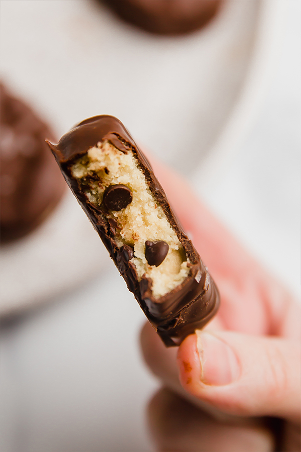 Person holding a chocolate covered cookie dough Easter egg missing a bite.