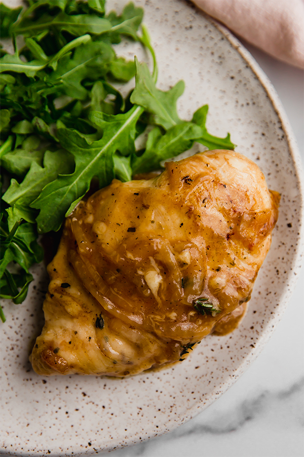 French onion chicken and greens on a plate.