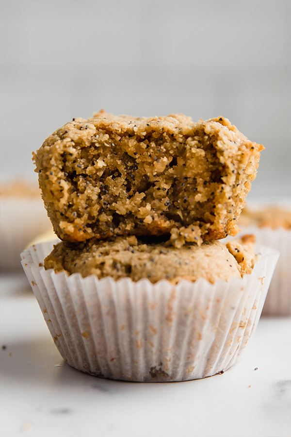 Stack of lemon zucchini poppyseed muffins missing a bite.