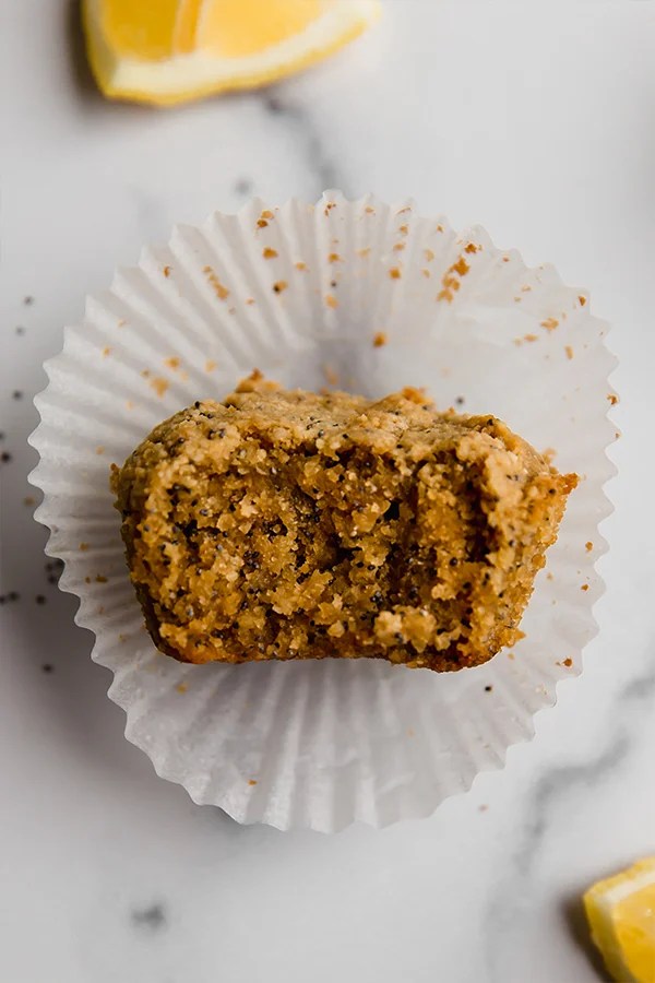 One lemon zucchini muffin with a bite on paper