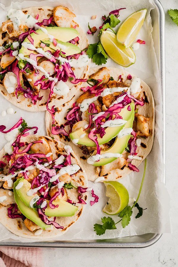 Fish tacos with slaw in a lined baking dish.