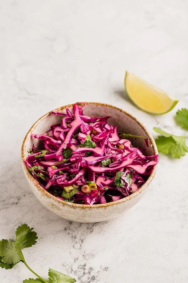 Cabbage slaw in a small bowl with lime and cilantro