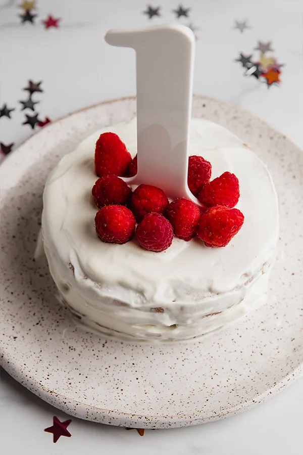 Raspberries and a number one on a cake.