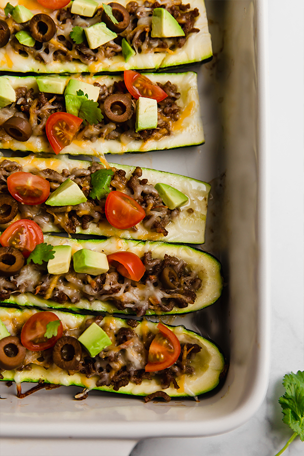 Up close view from top of stuffed zucchinis in baking dish