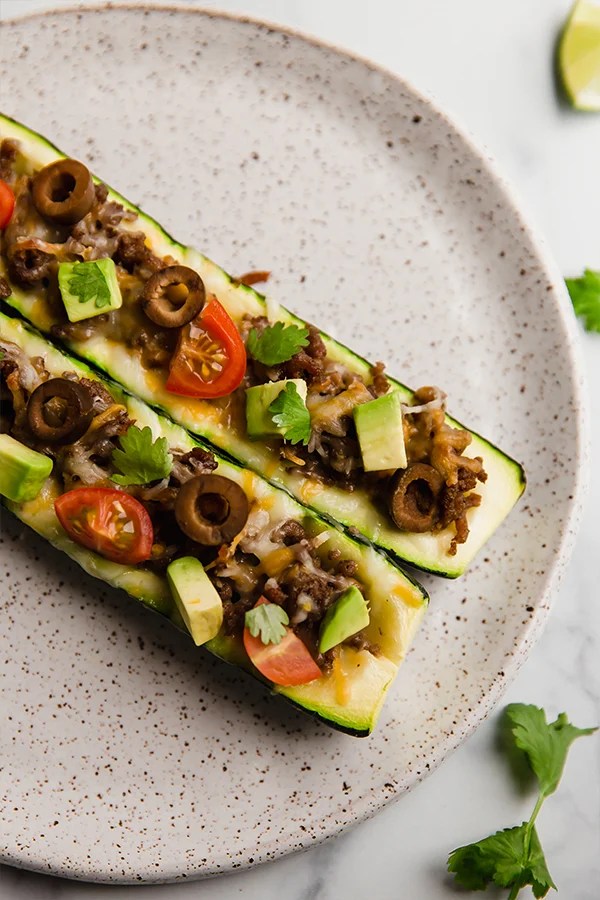 Taco-stuffed zucchini boats on a plate.