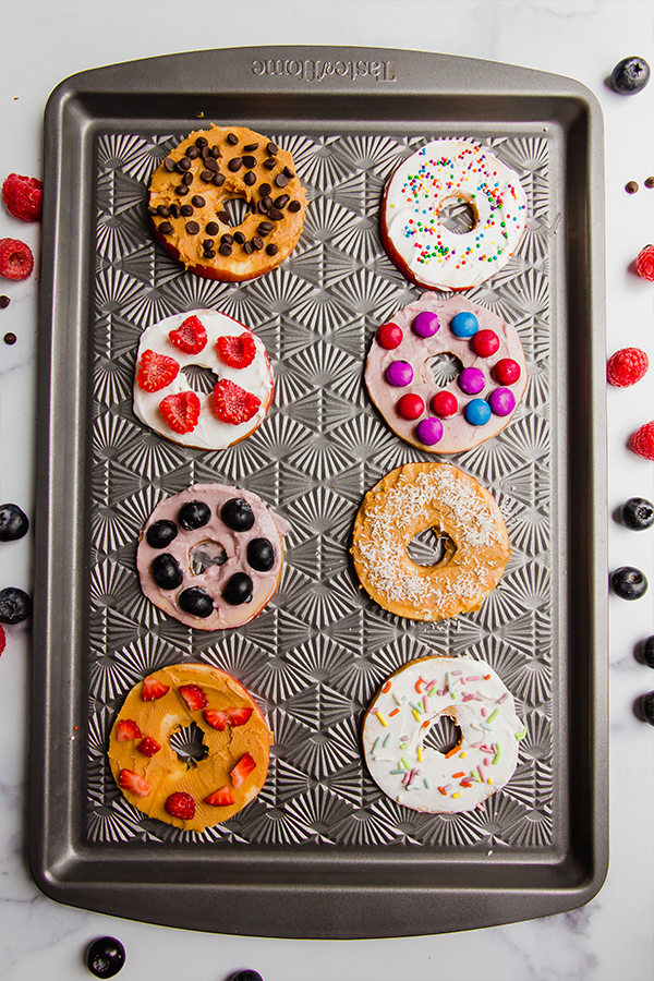 Several different apple \"donuts\" on a baking sheet.