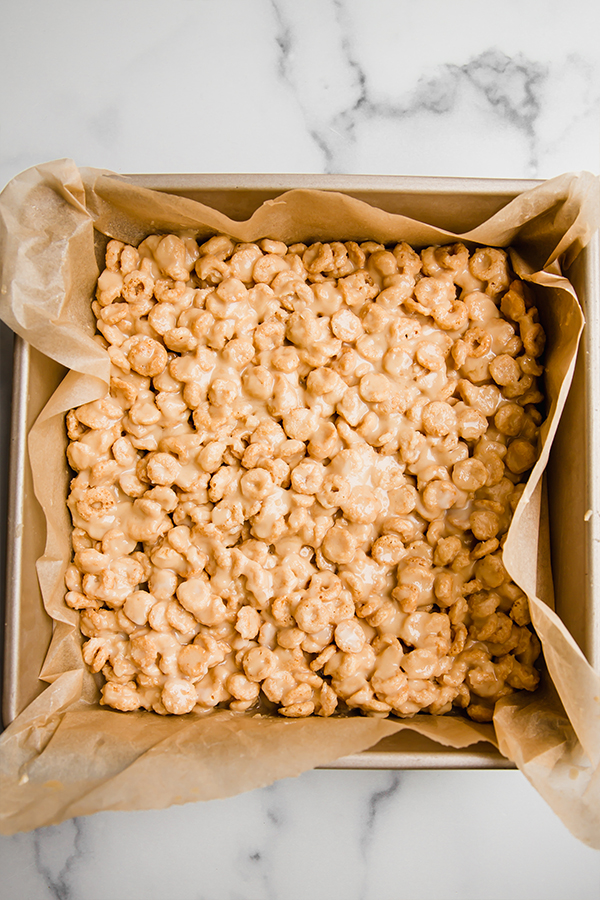 cereal bars pressd into a square pan ready to set in the fridge