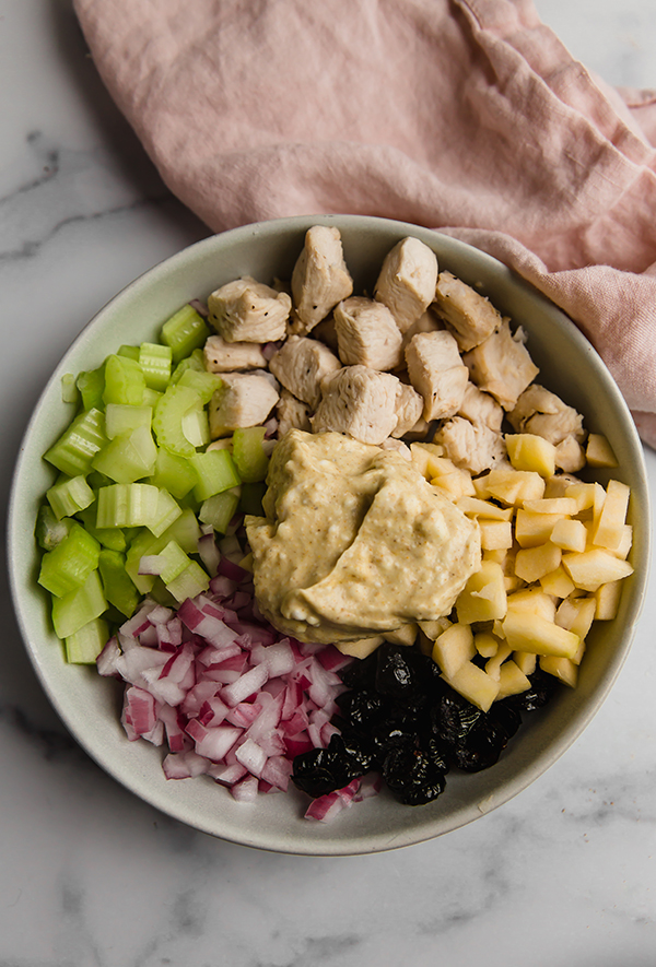 Ingredients for chicken salad in bowl with curry dressing ready to mix