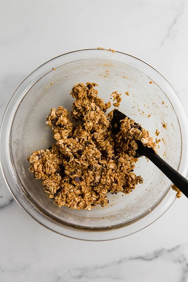 Ingredients for energy bites mixed together in glass bowl with spatula