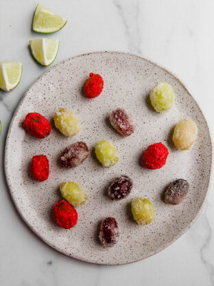 Different-colored sour patch kid grapes on a plate.
