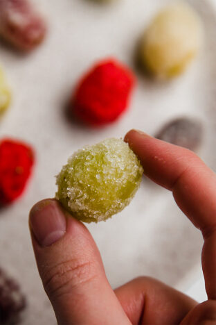Up close image of sour patch grape held between fingers