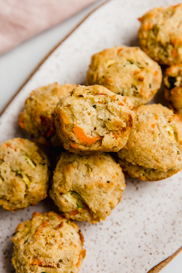 Veggie muffin missing a bite on a plate.