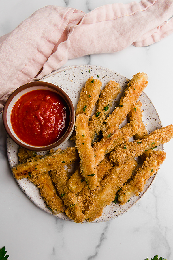 Zucchini fries on a plate with dip.