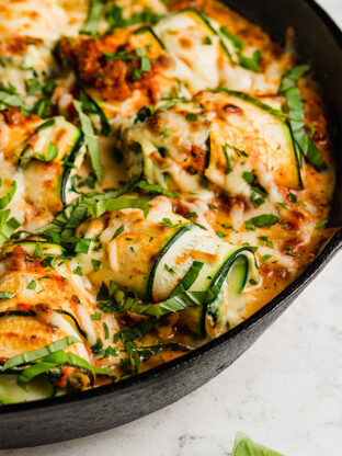 Zucchini roll ups topped with melted dairy-free cheese.