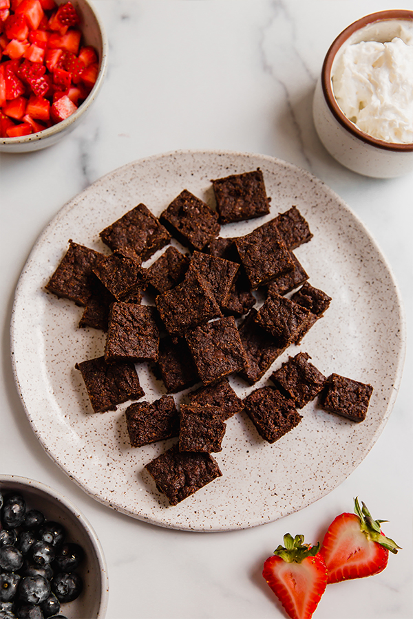 Brownie chunks on plate with other toppings in bowls