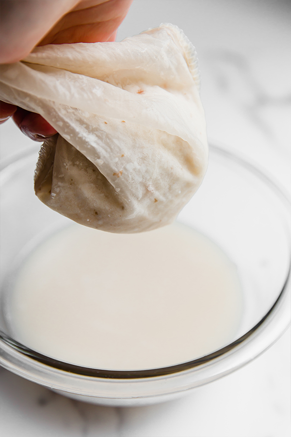Coconut milk straining through a nut milk bag.