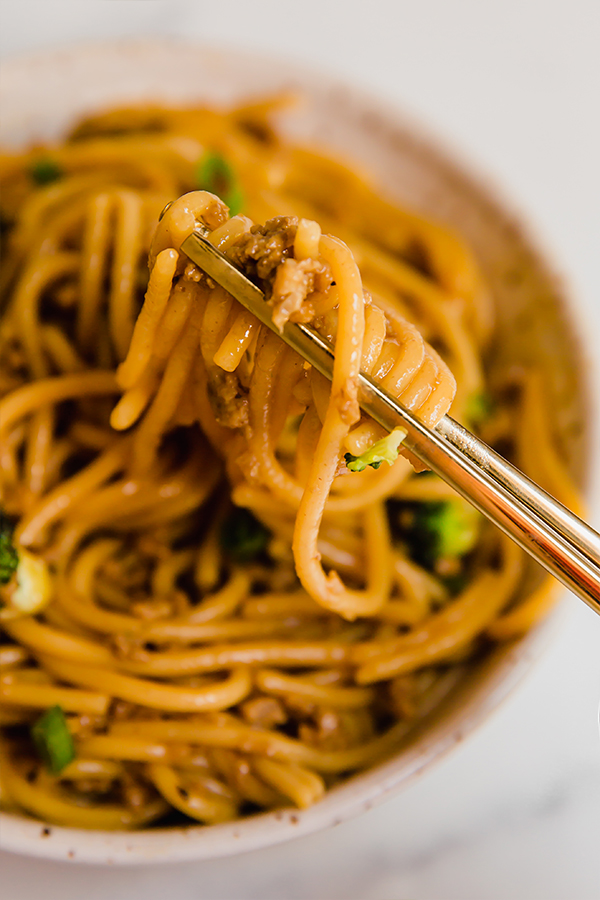 Mongolian ground beef with noodles served in a bowl with chopsticks