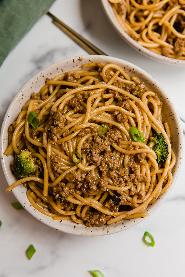 Top view of Mongolian ground beef with noodles served in a bowl with chopsticks