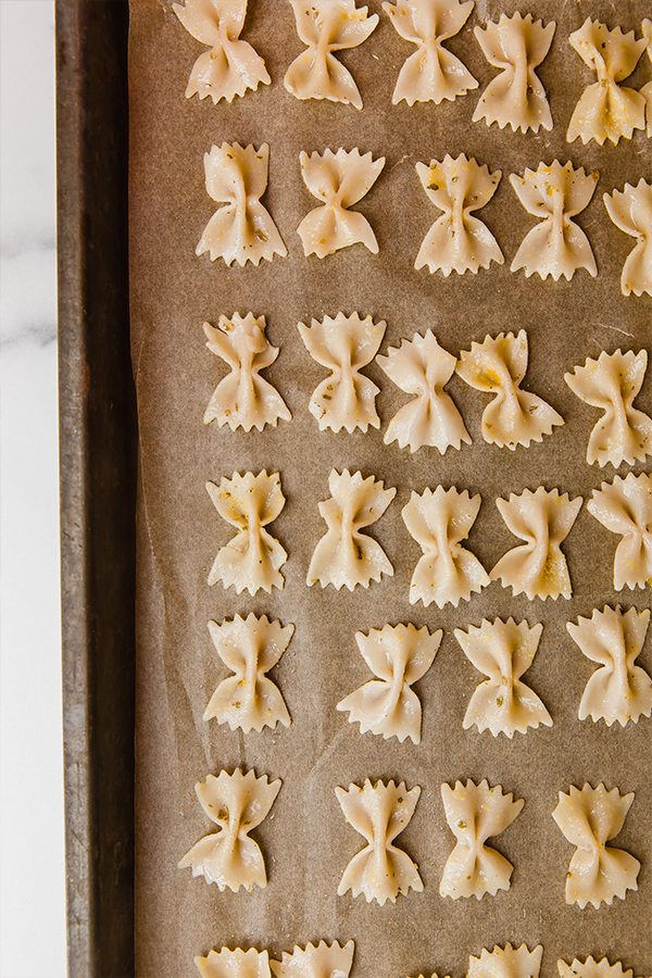 Cooked pasta on a lined baking sheet.
