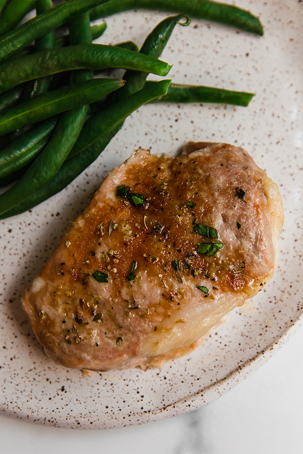 Pork chop on a plate with beans.