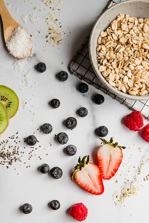 Fruit, seeds, and toppings on a marbled surface.