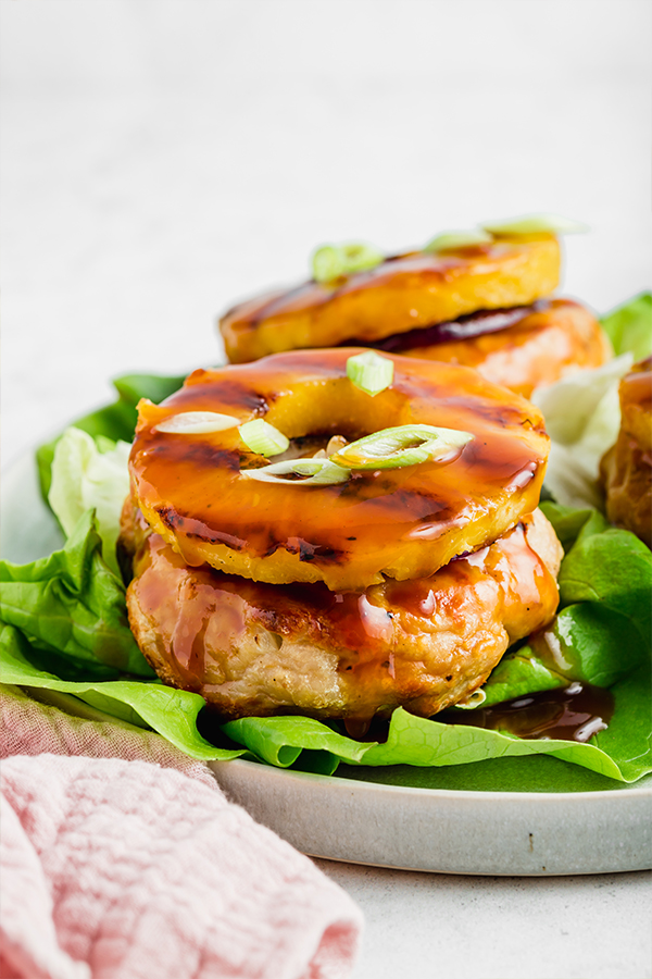 Up close side view of grilled chicken burger with pineapple ring on top