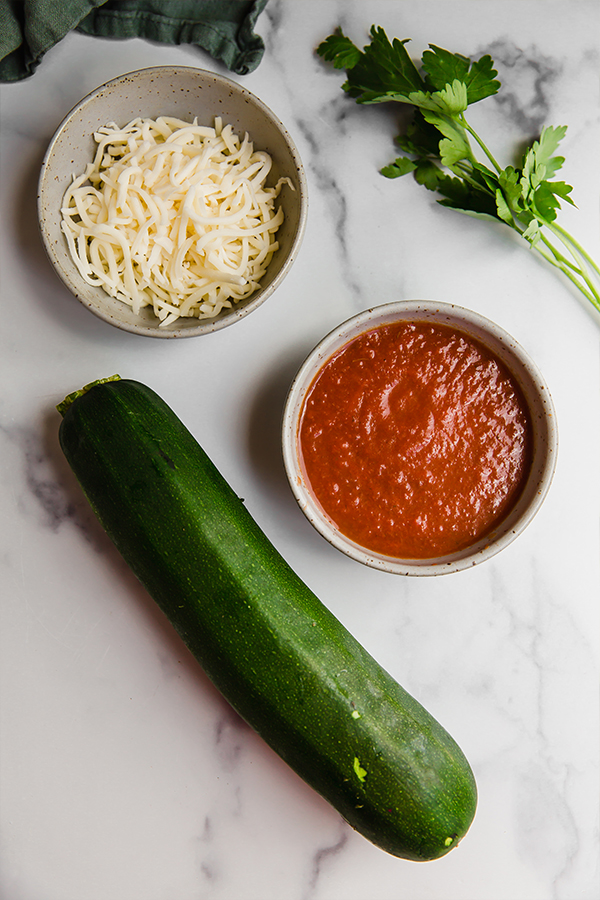 Pizza bites ingredients in bowls with zucchini on counter