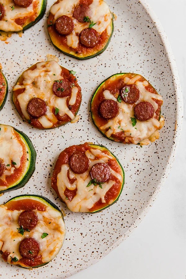Mini zucchini pepperoni pizza bites on a plate.
