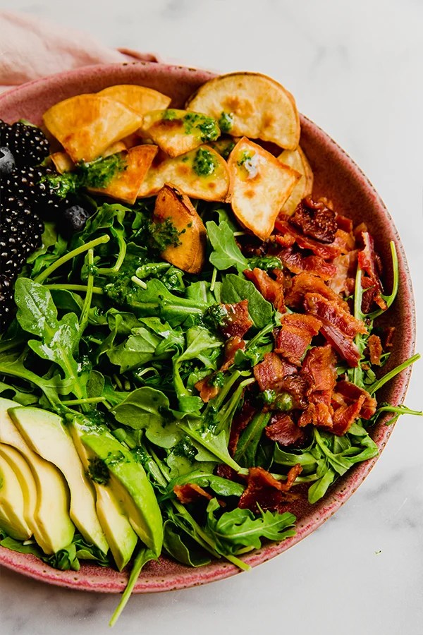 Breakfast salad with avocado and bacon in a bowl.