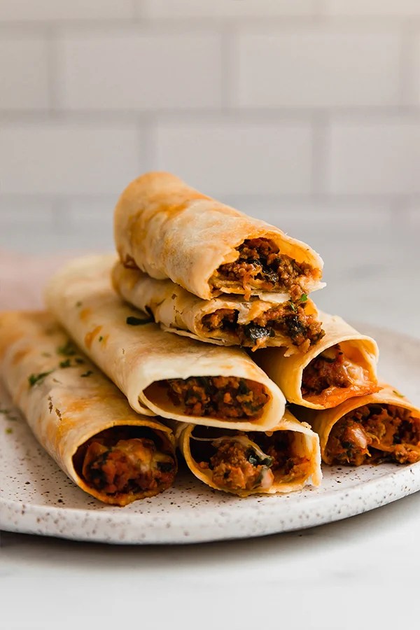 Gluten-free pizza roll ups stacked on a plate.