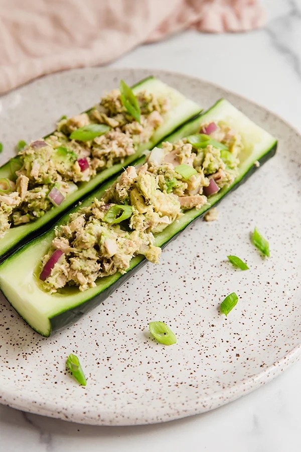 Two avocado tuna salad cucumber boats on a plate.
