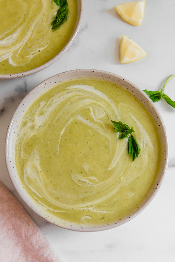Top view of zucchini soup in a bowl topped with basil