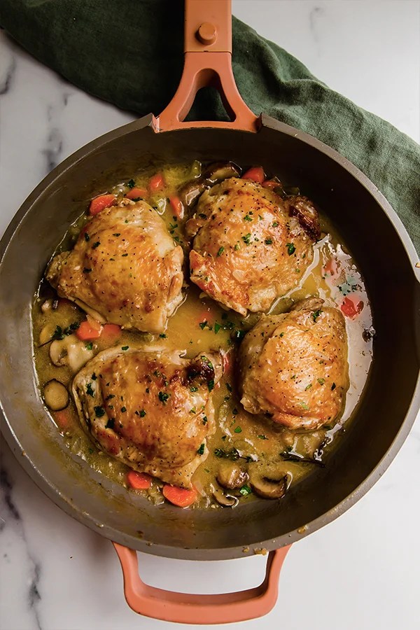 Top view of chicken thighs cooked in pan with sauce