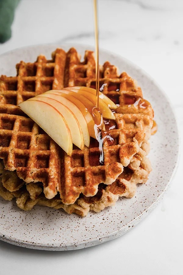 Syrup pouring over an apple waffle.