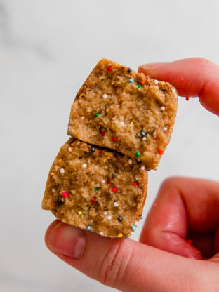 Person holding two cake batter protein bars.