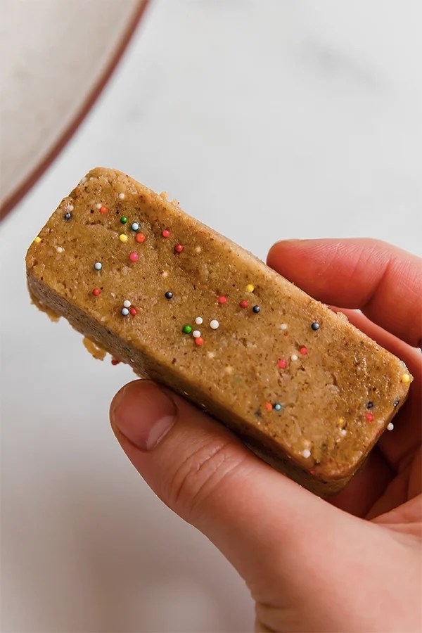 Person holding cake batter protein bar.