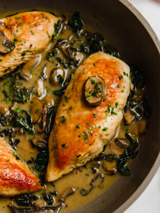 Chicken and creamed spinach with mushrooms in a pan.