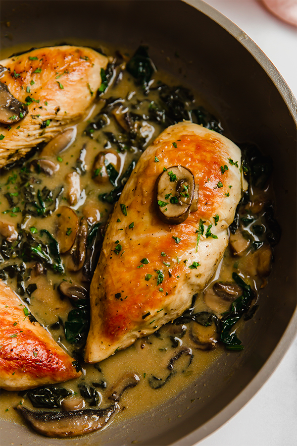 Chicken and creamed spinach with mushrooms in a pan.