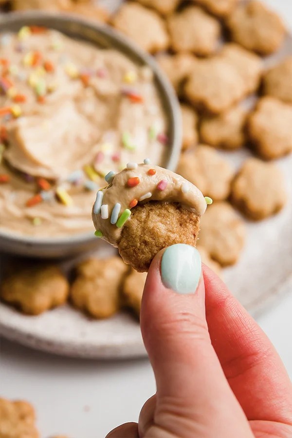 A Dunkaroo cookie with icing and sprinkles being lifted by a hand.